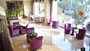 A hotel lobby with purple seating, a reception desk, and large windows with decorations. - Shenhang Yinju Mingzhu Hotel (Jiashan)