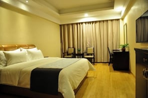 A hotel room with a bed, a desk, chairs, a small table, and a cabinet. - Shenhang Yinju Mingzhu Hotel (Jiashan)