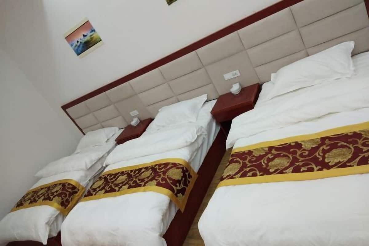 A hotel room with two beds, each with white bedding and a decorative red and gold bedspread.