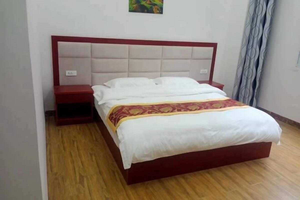 A bed with a headboard, a bedside table, and a wall-mounted light switch.