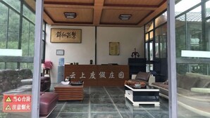 A reception area with a wooden ceiling, a reception desk, and seating arrangements. - Yunshang Holiday Manor (Luoping)