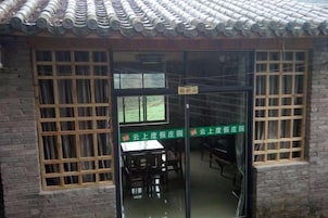 Un edificio tradicional con techo de tejas, puerta de madera con paneles de vidrio y un letrero que indica un jardín de té.
