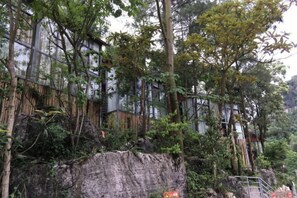 A building with a modern architectural design, surrounded by dense vegetation and trees. - Yunshang Holiday Manor (Luoping)