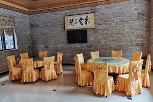 Una habitación con pared de ladrillo, televisor montado y una mesa redonda con sillas.