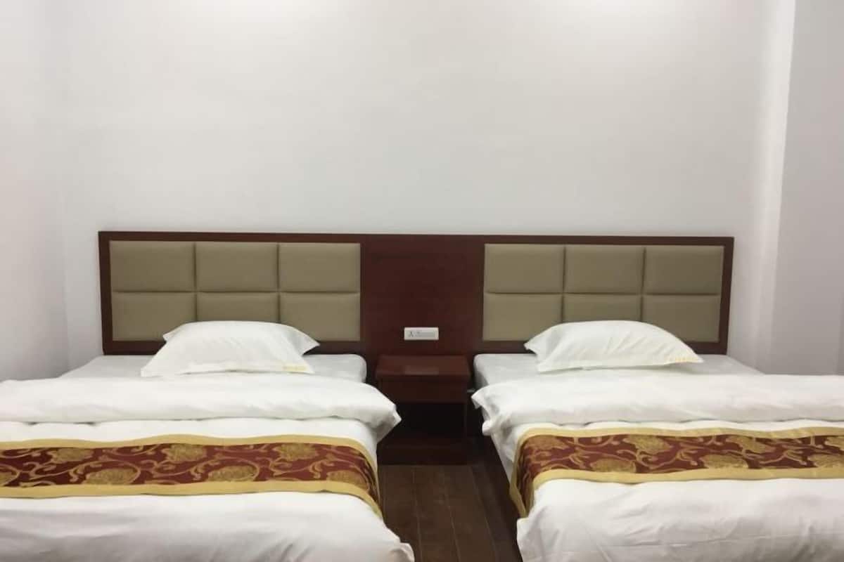 A hotel room with two beds, a wooden headboard, and a small bedside table.