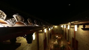 A dimly lit corridor with a wooden bench and a table in the center, leading to a room with a bed and a nightstand. - Zhongting Xiyun Hotel (Songpan)