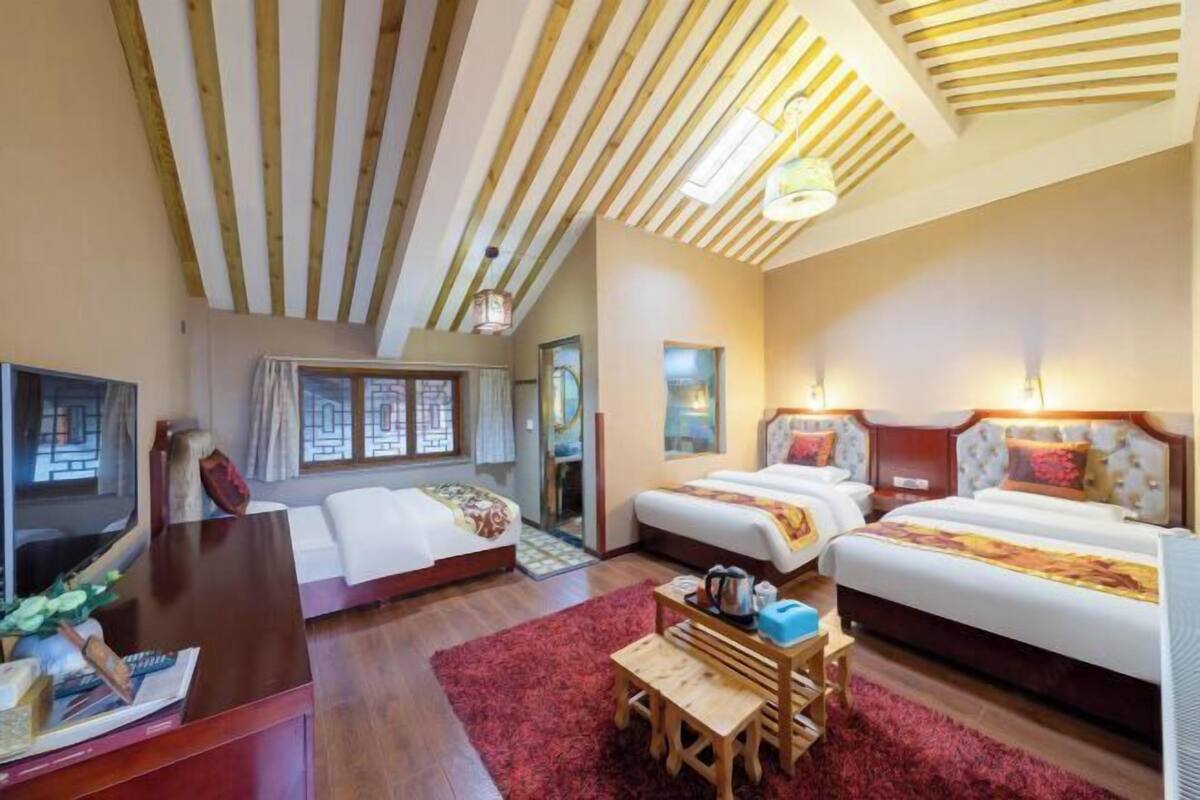 Une chambre d’hôtel avec deux lits, un bureau avec une chaise, une télévision et un tapis rouge.