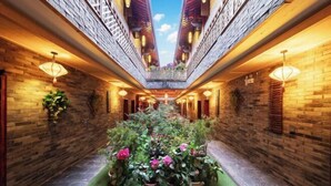 A corridor with brick walls, potted plants, and hanging lights. - Zhongting Xiyun Hotel (Songpan)