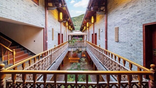 A corridor with a wooden railing, brick walls, and hanging lanterns. - Zhongting Xiyun Hotel (Songpan)