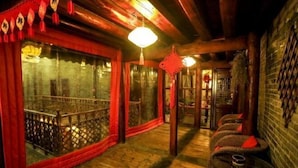 A traditional wooden interior with a wooden floor, red curtains, and a seating area with woven chairs. - Zhongting Xiyun Hotel (Songpan)