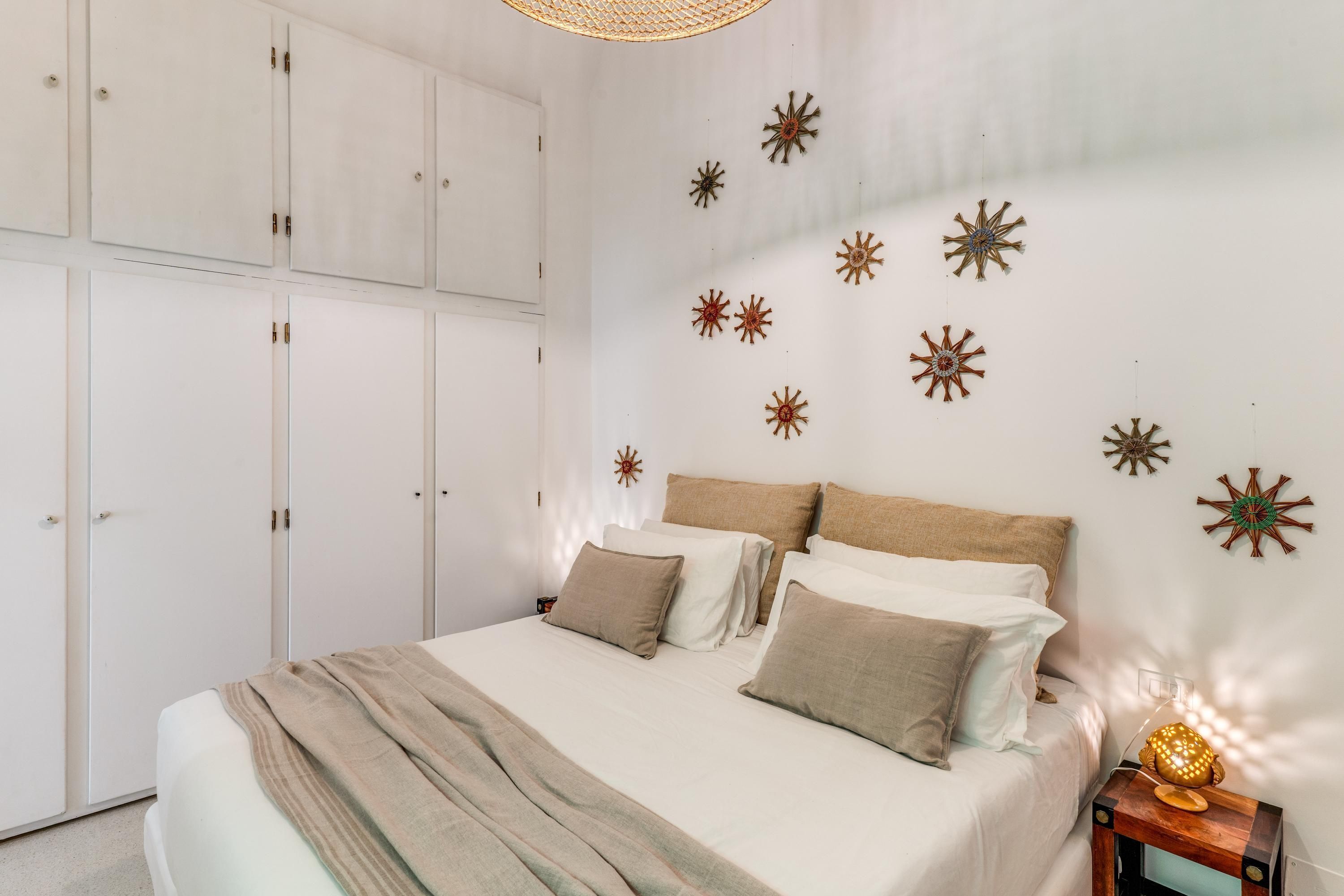 Ein Schlafzimmer mit einem Bett, einem weißen Kleiderschrank und Wanddekorationen.