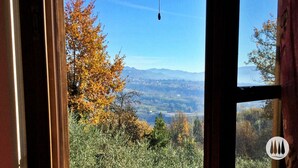 A view through a window with a clear sky, autumn foliage, and distant mountains. - The vacation home is nestled in the Tuscan countryside with a private pool (Gallicano)