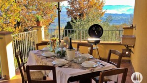 A table set outdoors with a view of mountains and autumn foliage. - The vacation home is nestled in the Tuscan countryside with a private pool (Gallicano)