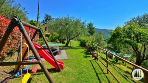A playground with swings and a slide, surrounded by well-maintained grass and trees. - The vacation home is nestled in the Tuscan countryside with a private pool (Gallicano)