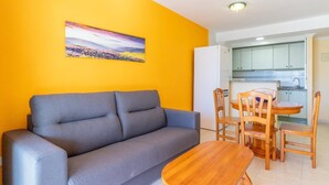 A living room with a gray sofa, a wooden dining table, and a painting on the wall. - Zafiro 26B - Grupo Turis - Calpe, Costa Blanca (Calpe)
