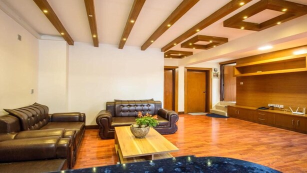 A modern living room with leather sofas, a wooden coffee table, and a built-in wooden cabinet. - MeroStay 161 SN HOTEL (Lalitpur)