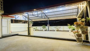 An outdoor covered area with a metal roof, potted plants, and a concrete floor. - MeroStay 161 SN HOTEL (Lalitpur)
