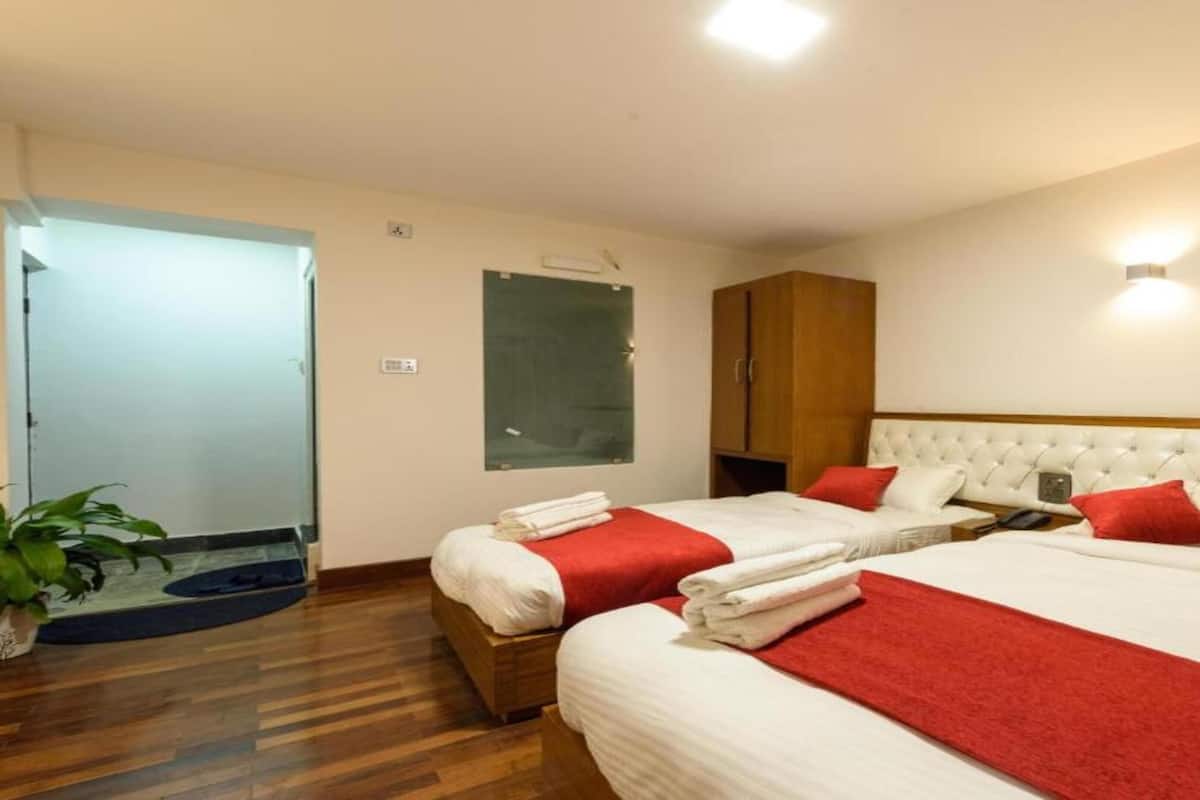 Een hotelkamer met twee bedden, een houten garderobe, een groen prikbord aan de muur en een potplant.
