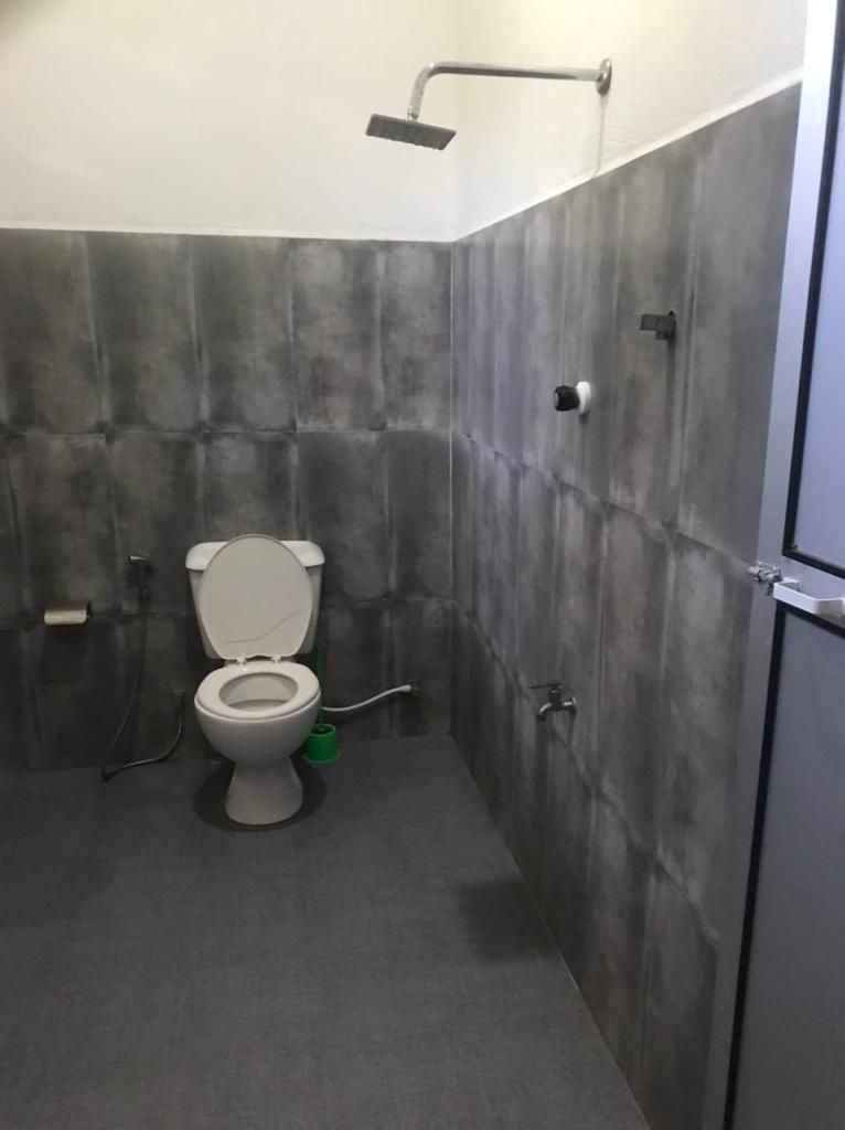 A bathroom with a toilet, a shower, and a towel rack.