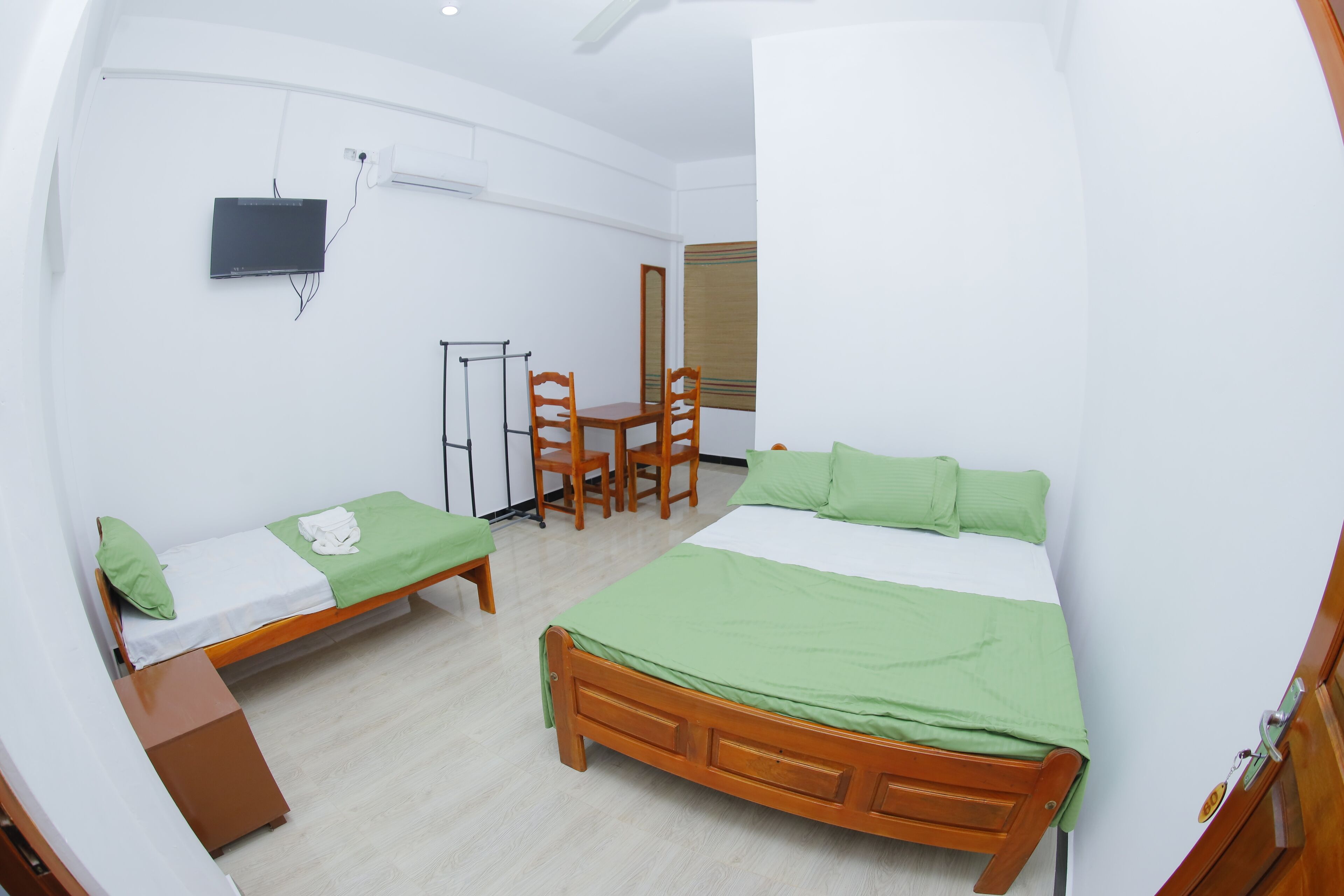 A room with two beds, a desk, chairs, a TV, and a mirror.