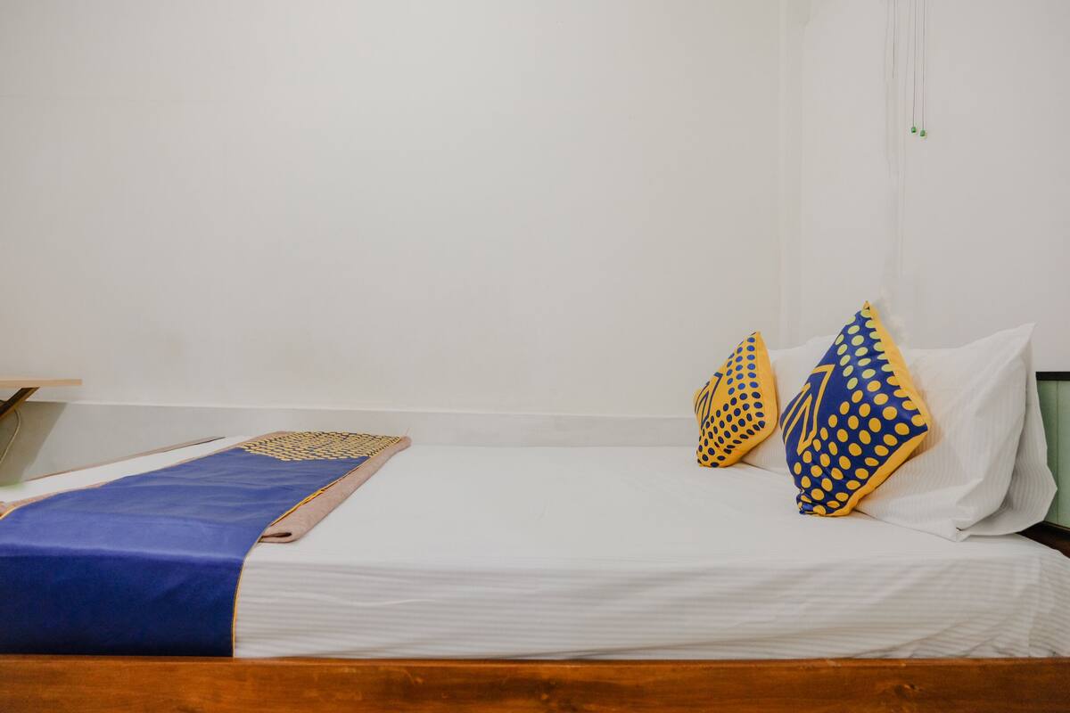 A neatly made bed with white linens and two decorative pillows with a polka dot pattern.