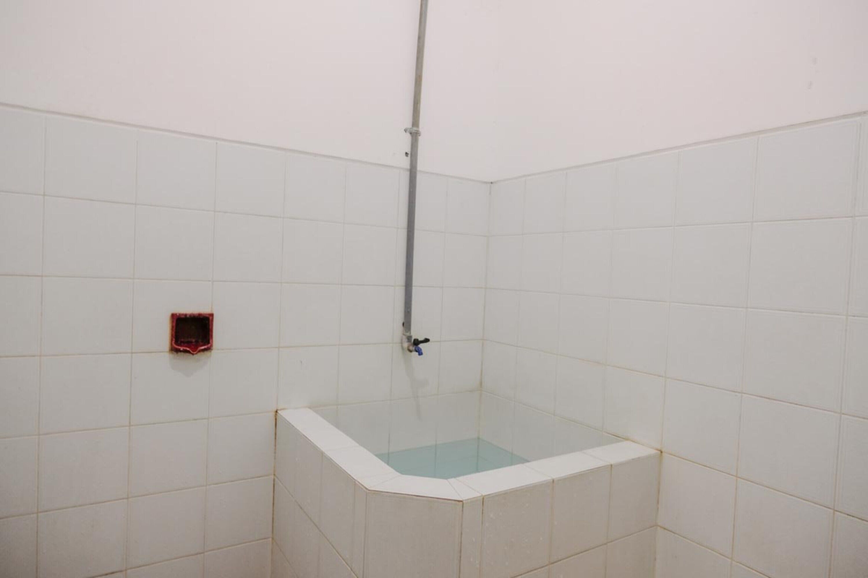 A small, tiled bathroom with a corner bathtub and a showerhead.