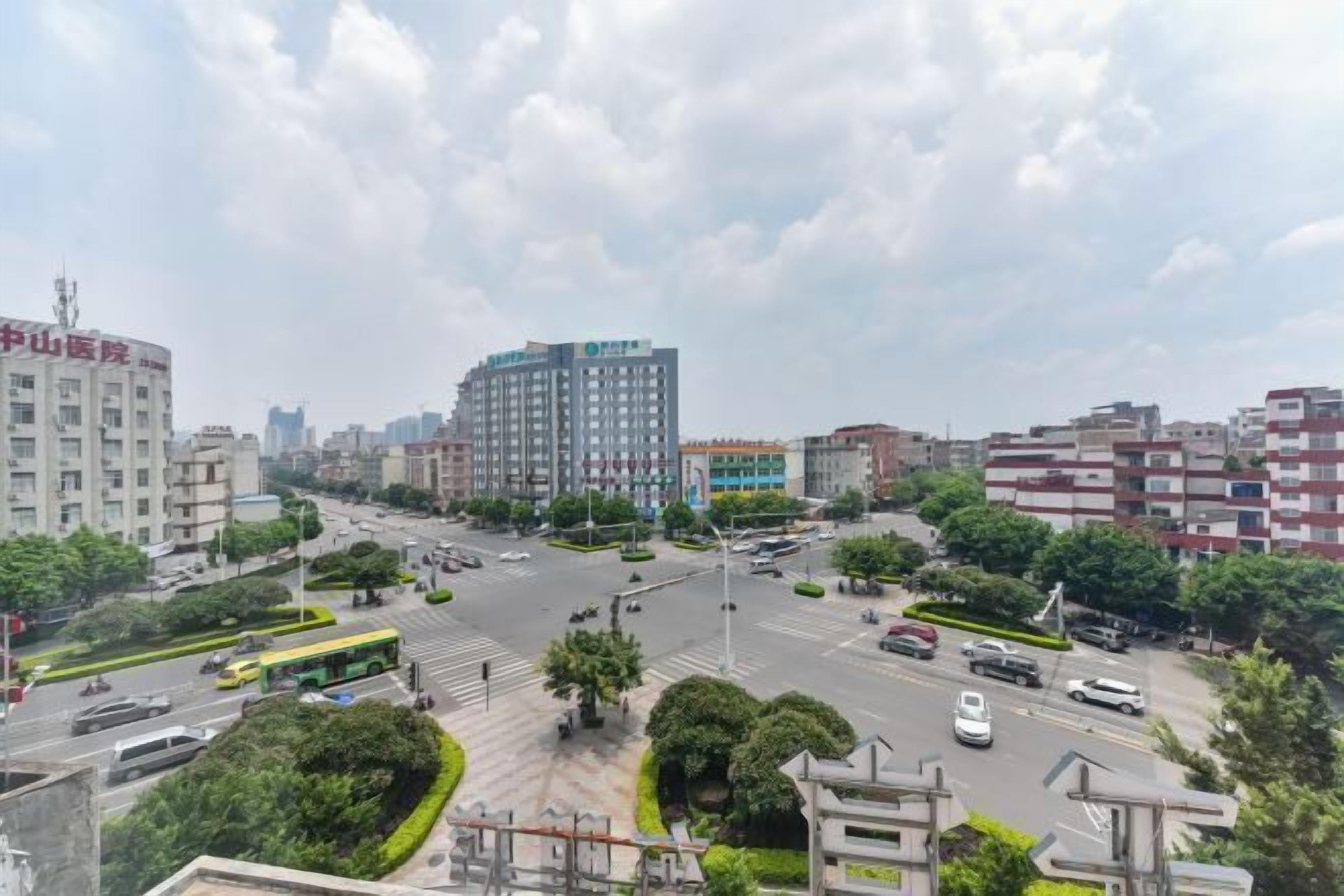 Une vue urbaine mettant en évidence un bâtiment imposant portant l’inscription « 中山医院  » (hôpital Chuan Shan) et un immeuble moderne de grande hauteur.