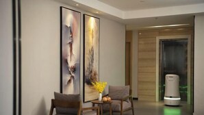A modern lobby with two framed abstract paintings, a reception desk with a vase of flowers, and a self-service kiosk. - Qianyi Yicheng Hotel (Yulin Shizi Street Yuntian Palace) (Yulin)
