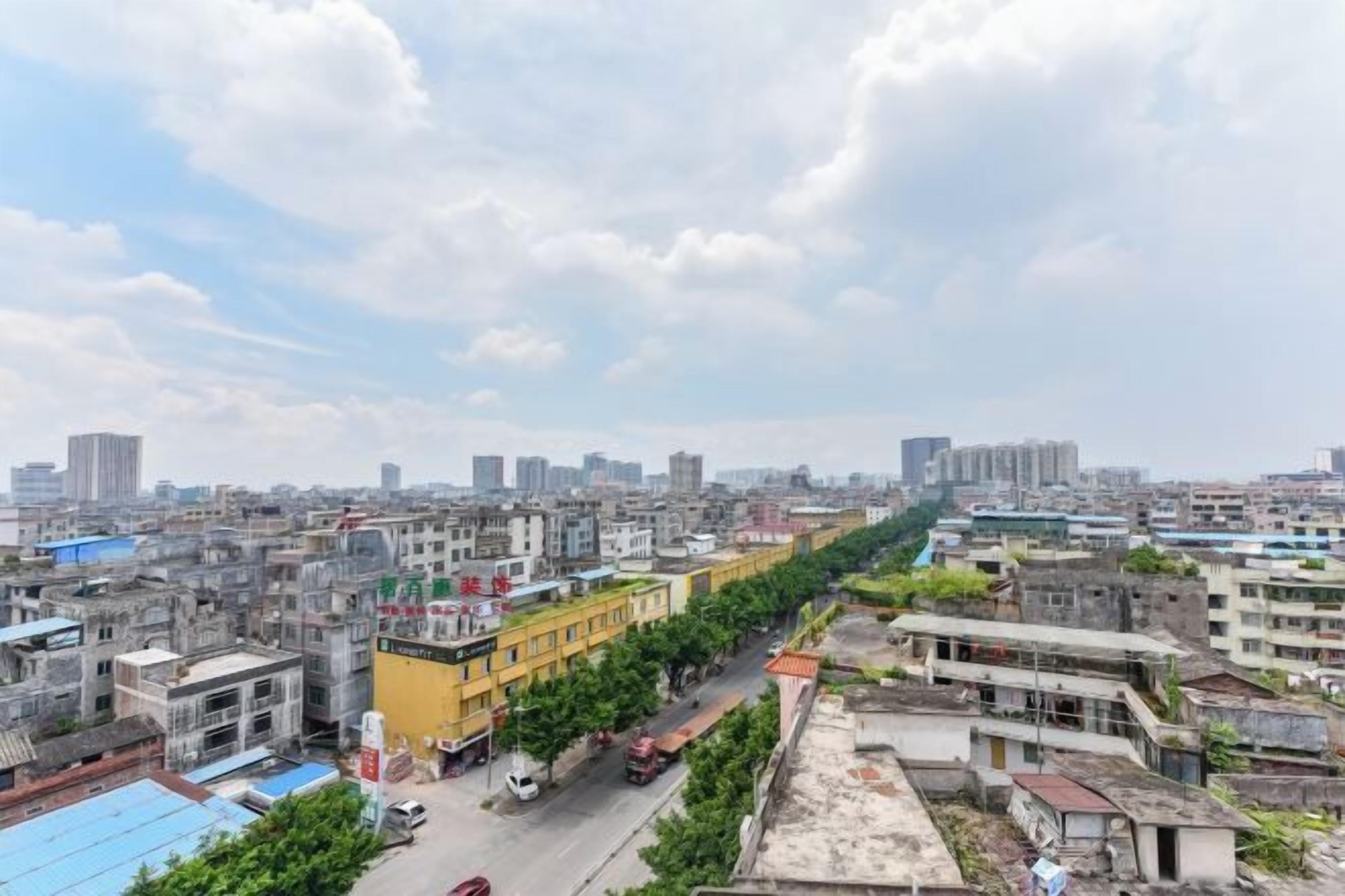 Un paisaje urbano con una mezcla de edificios altos y bajos, una avenida principal y algo de vegetación a lo largo de las calles.