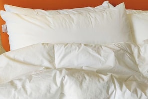 A bed with white bedding and pillows against an orange wall. - Qianyi Yicheng Hotel (Yulin Shizi Street Yuntian Palace) (Yulin)