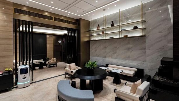 A modern interior with a round table, sofas, a robot, and a fireplace. - Qianyi Yicheng Hotel (Yulin Shizi Street Yuntian Palace) (Yulin)