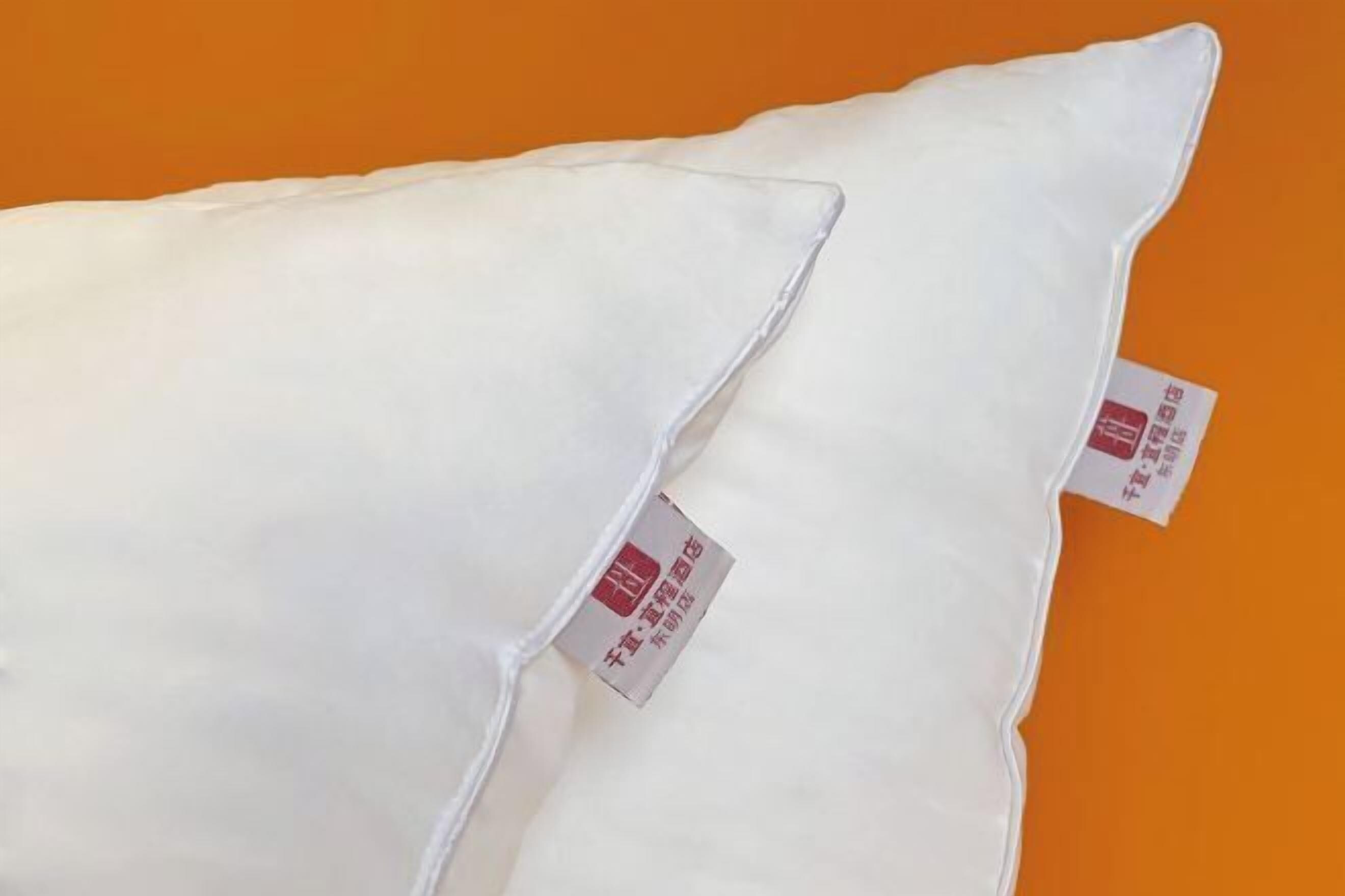 Two white pillows with labels on an orange background.