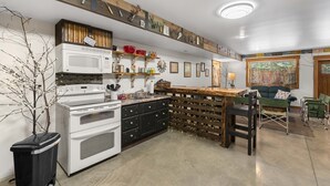A kitchen with a white stove, black cabinets, and a wooden island. There are various kitchen utensils hanging on the wall above the island. - River's Bend Lodge- Hot Tub, Fire Pit, Games & Ski (Leavenworth)