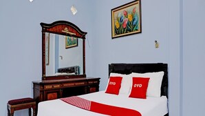 A bedroom with a bed, a wooden dresser, a mirror, and a painting on the wall. - OYO 92359 Kost Maluku 36 Family Residence (Kanigoro)