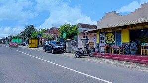 A street scene with a restaurant featuring a yellow awning and outdoor seating. - OYO 92359 Kost Maluku 36 Family Residence (Kanigoro)