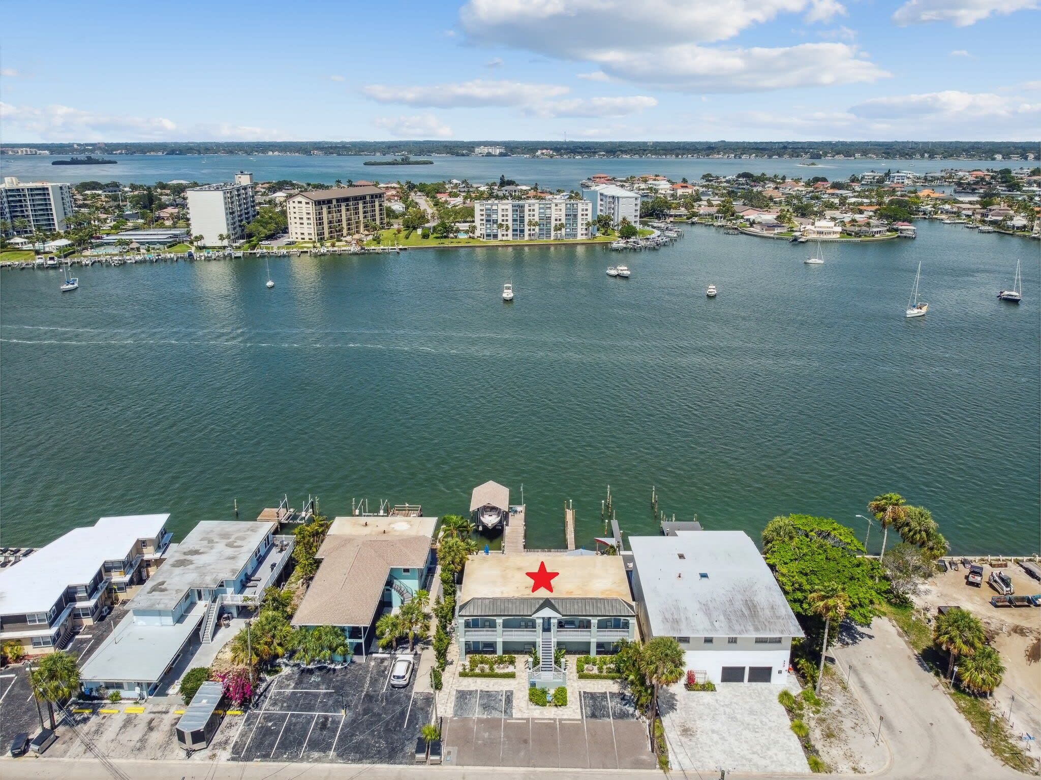 An aerial view of a marina with boats, buildings, and a prominent red star on a building.