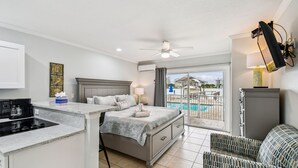 Un dormitorio con cama, mesita de noche y vista a una piscina.