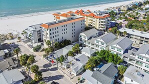 Un hotel frente al mar con varias construcciones, una playa al fondo y cielo despejado.