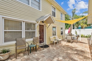 Relax on the patio with a seating area featuring a table and chairs, surrounded by lush greenery and a shaded canopy.