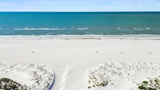 Una playa con vista clara al océano y dunas de arena.