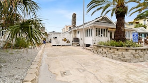 Une propriété située en bord de mer, avec un chemin de pierre menant à une maison dotée d’une cheminée en pierre et d’un panneau bleu indiquant une « zone de stationnement interdite ».