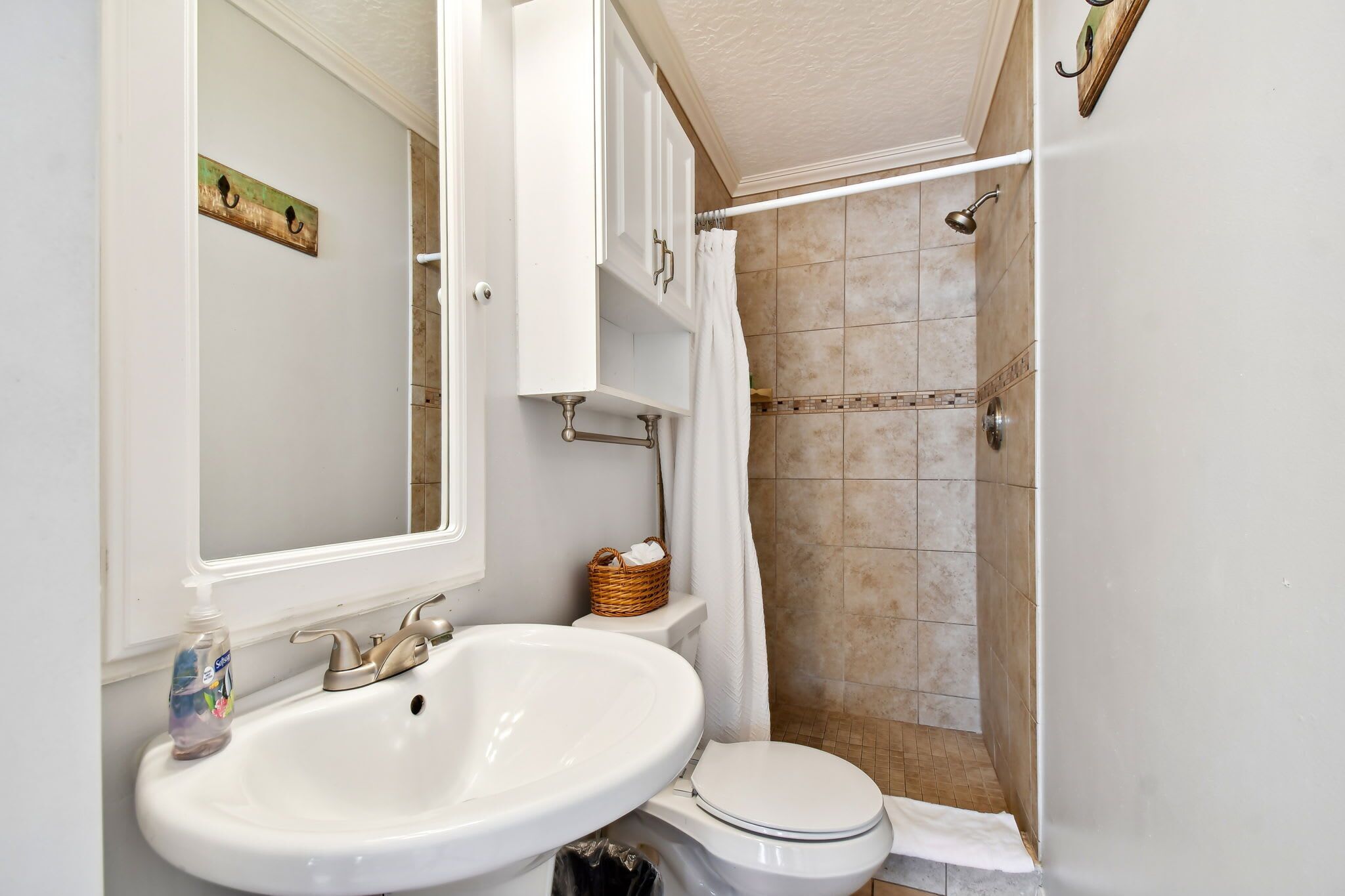 Et badeværelse med vask, toilet og brusebad.