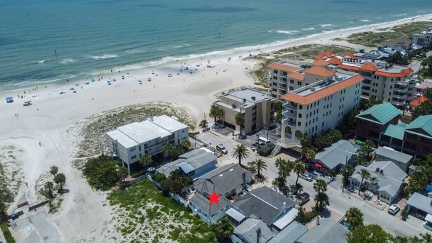 An aerial view of a beachside hotel with multiple buildings, a sandy beach, and the ocean.