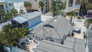 A residential building with a sloped roof, multiple balconies, and a fenced backyard with outdoor furniture.
