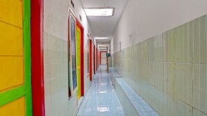 Un pasillo largo y estrecho con puertas de colores y pisos de baldosas azul claro.