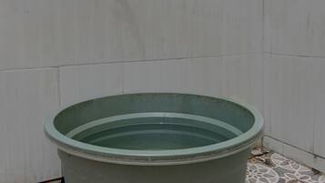 Una piscina grande y verde, circular, con un grifo en la pared de fondo, ubicada sobre un suelo de baldosas estampadas.