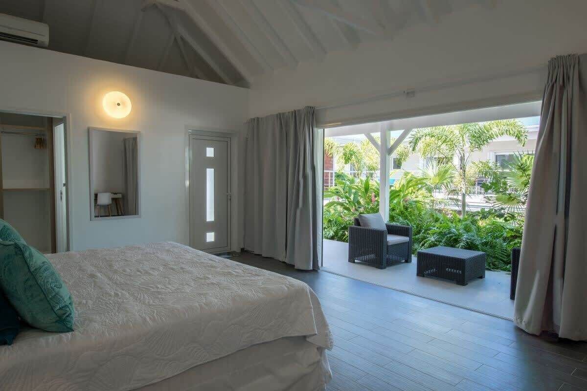 Ein Schlafzimmer mit einem Bett, einem Nachttisch, einem Spiegel und einem Fenster mit Vorhängen.