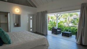 Un dormitorio con cama, mesita de noche, espejo y ventana con cortinas.