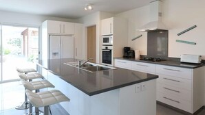 Una cocina moderna con una isla grande, armarios blancos y horno empotrado.