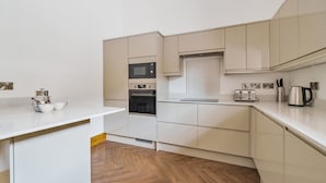 Una cocina moderna con armarios blancos, horno integrado, microondas y tostadora.